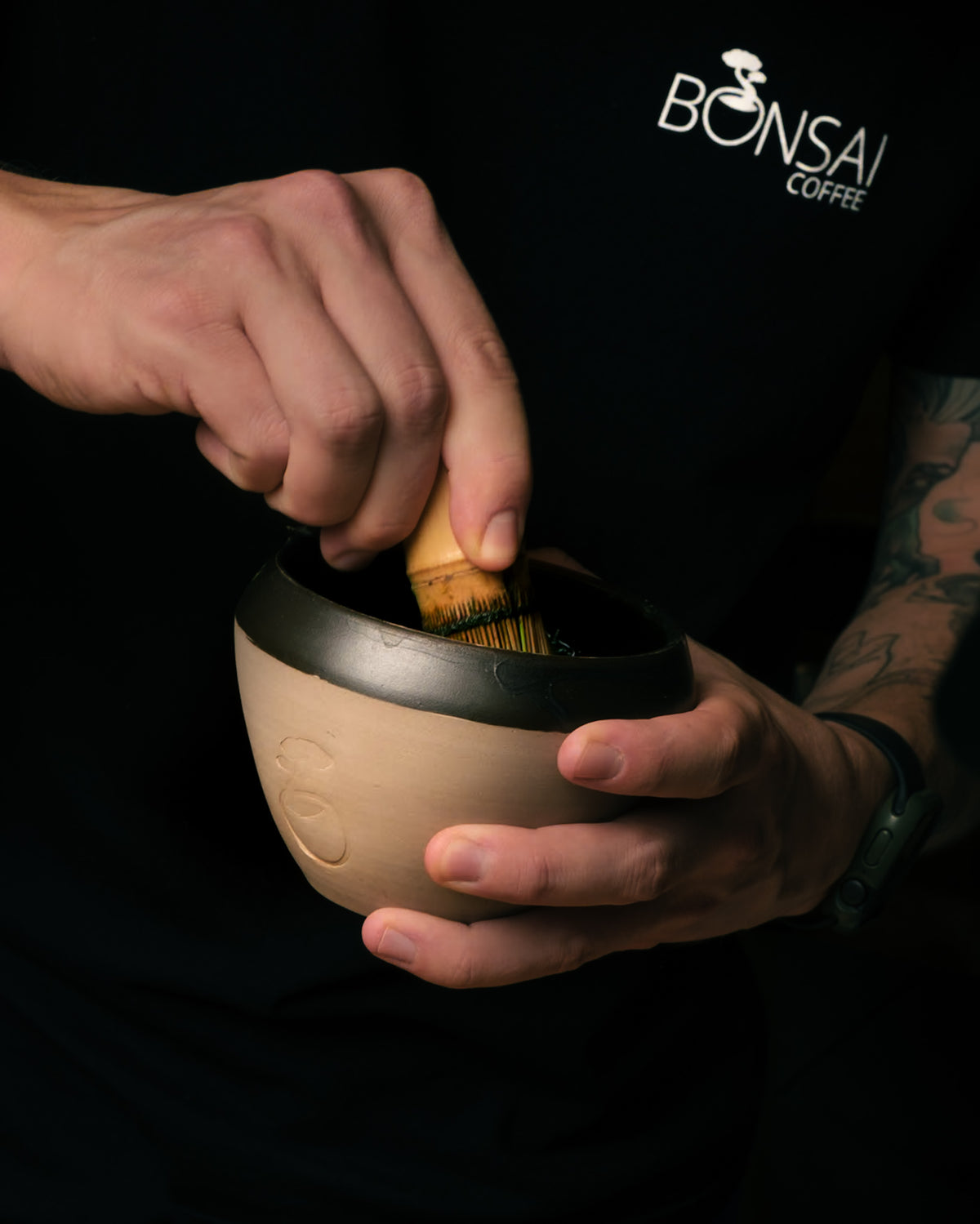 Hands whisking matcha in a ceramic bowl