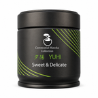 Yūhi ceremonial matcha tin beside bright green matcha powder on white, smooth sweet Japanese green tea